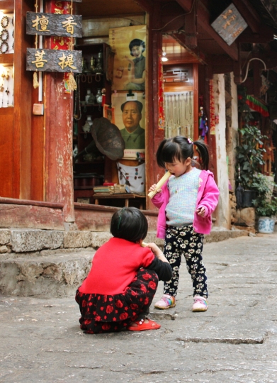 Zwei Mädchen knabbern Zuckerrohr in Lijiang Old Town